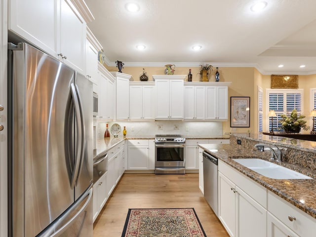 kitchen with white cabinetry, sink, stainless steel appliances, tasteful backsplash, and dark stone countertops