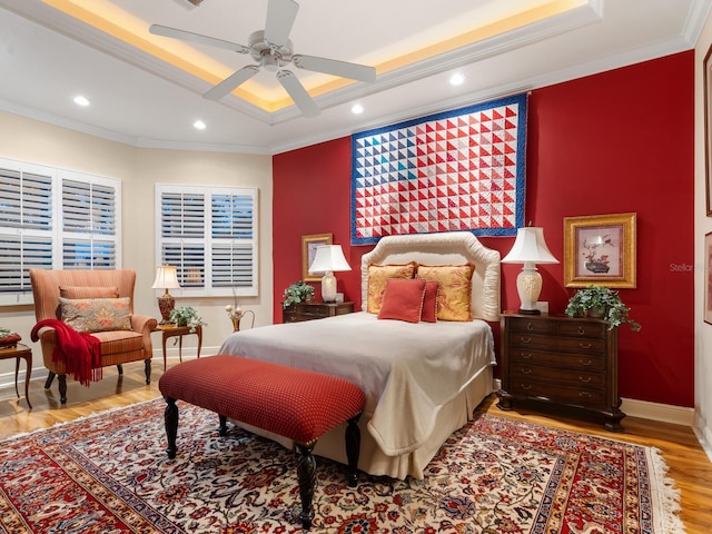 bedroom featuring a raised ceiling, ceiling fan, light wood-type flooring, and ornamental molding