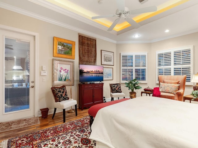 bedroom with hardwood / wood-style floors, ceiling fan, crown molding, and a tray ceiling