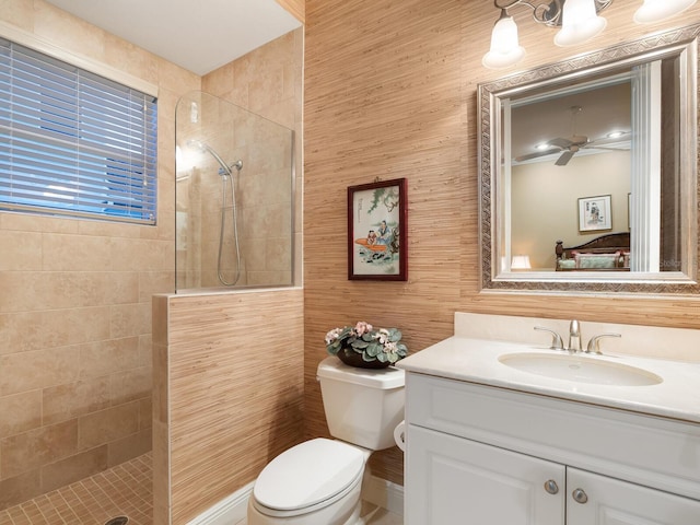 bathroom featuring a tile shower, ceiling fan, vanity, and toilet