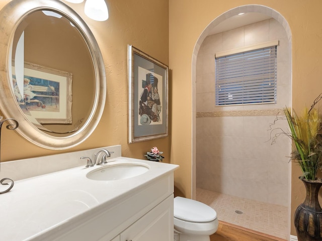 bathroom with vanity, toilet, and tiled shower