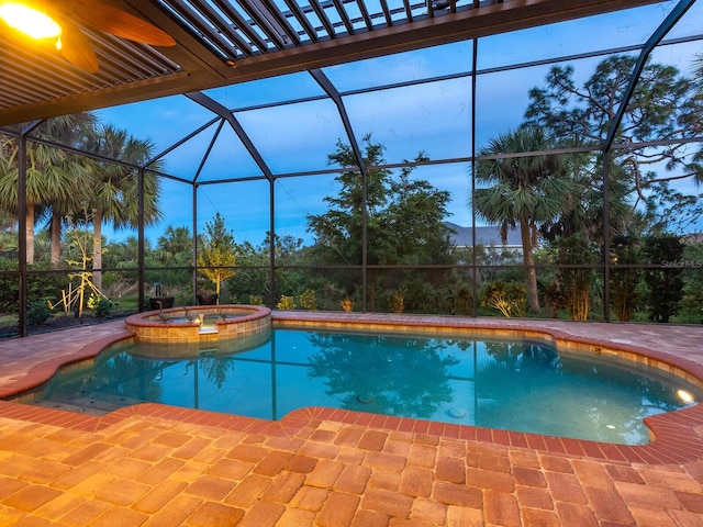 pool at dusk with glass enclosure, an in ground hot tub, and a patio