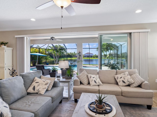 living room with a water view, ornamental molding, and a textured ceiling