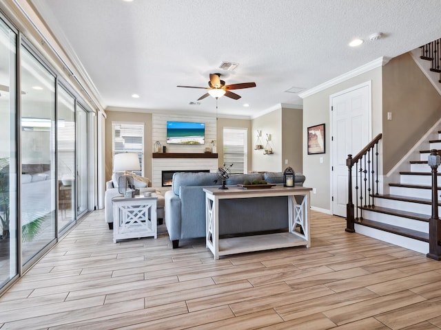 living room with crown molding, ceiling fan, a healthy amount of sunlight, and a textured ceiling