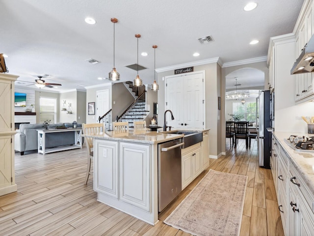 kitchen featuring a center island with sink, white cabinets, ceiling fan, decorative light fixtures, and stainless steel appliances