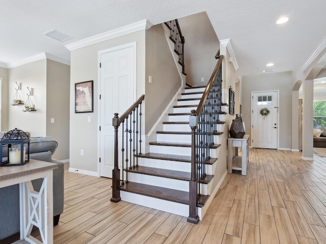 stairway with a textured ceiling and crown molding