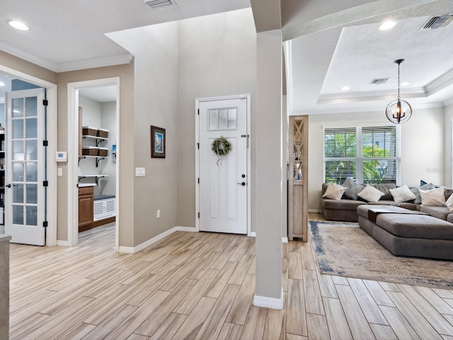 foyer entrance featuring a tray ceiling, crown molding, and a notable chandelier