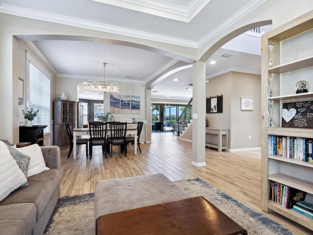 living room with light hardwood / wood-style floors, ornamental molding, and an inviting chandelier