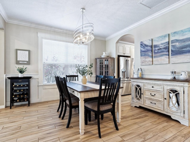 dining space with ornamental molding, a textured ceiling, and a notable chandelier