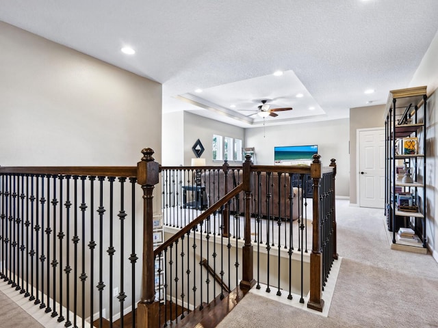 stairs featuring carpet flooring, a textured ceiling, a raised ceiling, and ceiling fan