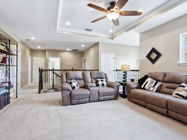 carpeted living room featuring a textured ceiling, a raised ceiling, ceiling fan, and crown molding