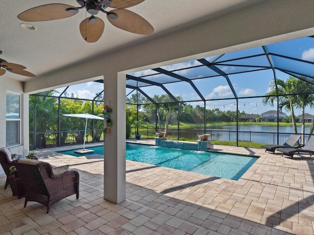 view of swimming pool featuring glass enclosure, ceiling fan, and a water view