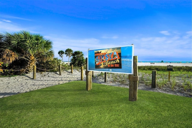 view of home's community with a beach view, a water view, and a yard