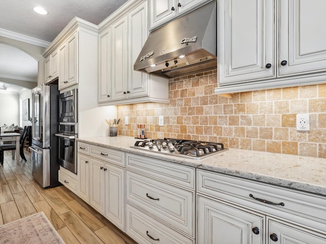 5930 Anise Dr, Sarasota, FL 34238 - kitchen featuring under cabinet range hood, ornamental molding, arched walkways, light stone countertops, and appliances with stainless steel finishes