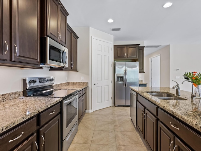 kitchen with light stone countertops, sink, dark brown cabinetry, and stainless steel appliances