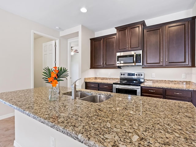 kitchen with light stone countertops, sink, dark brown cabinetry, and stainless steel appliances