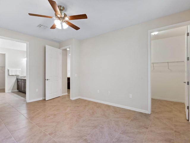 unfurnished bedroom with a spacious closet, ensuite bath, light tile patterned floors, a closet, and ceiling fan