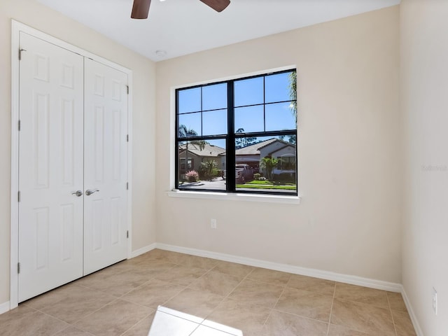 unfurnished bedroom featuring ceiling fan, light tile patterned floors, and a closet