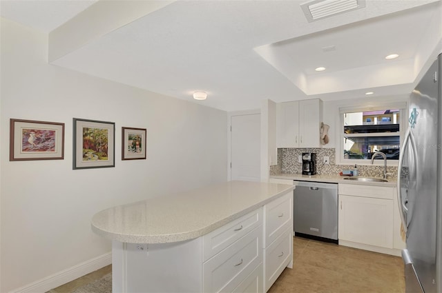 kitchen featuring appliances with stainless steel finishes, backsplash, sink, white cabinets, and a center island