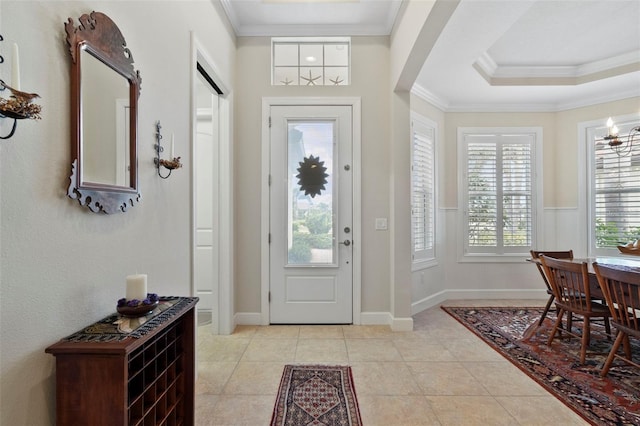 tiled entryway featuring a tray ceiling and ornamental molding