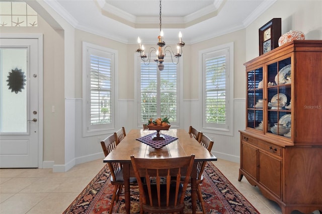 dining area with a tray ceiling, plenty of natural light, ornamental molding, and a notable chandelier