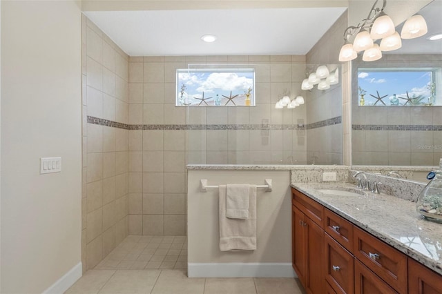 bathroom featuring tile patterned flooring, plenty of natural light, tiled shower, and vanity