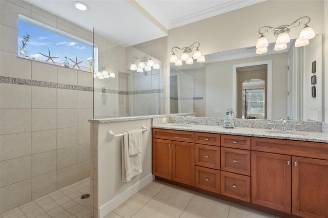 bathroom featuring tile patterned flooring, a tile shower, vanity, and ornamental molding