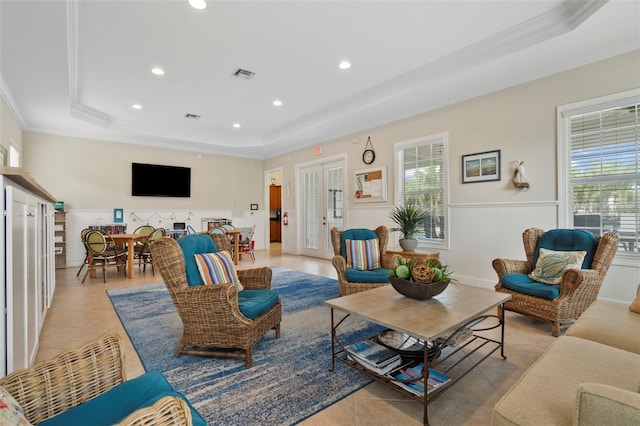 living room with a raised ceiling, light tile patterned floors, crown molding, and french doors