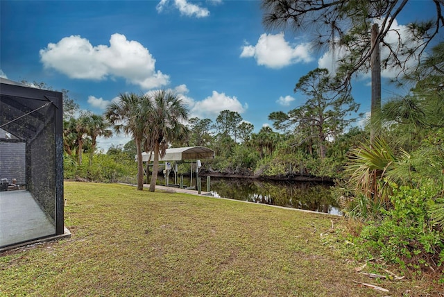 view of yard featuring a lanai, a water view, and a boat dock