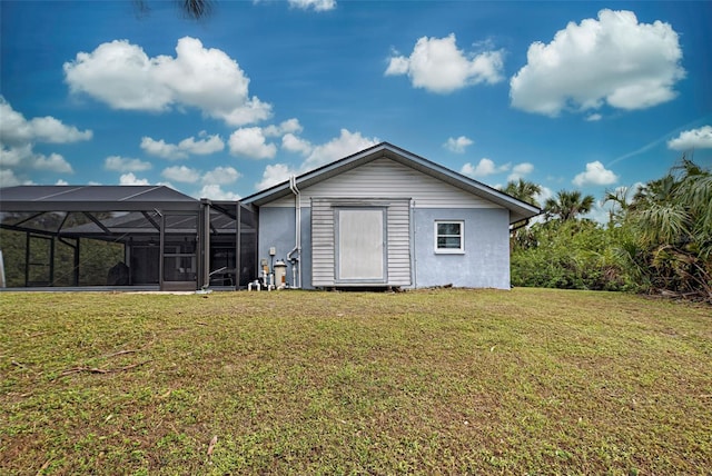 rear view of house featuring a lanai and a lawn