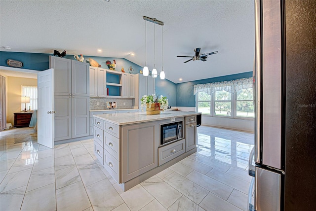 kitchen featuring gray cabinetry, black microwave, hanging light fixtures, lofted ceiling, and a kitchen island