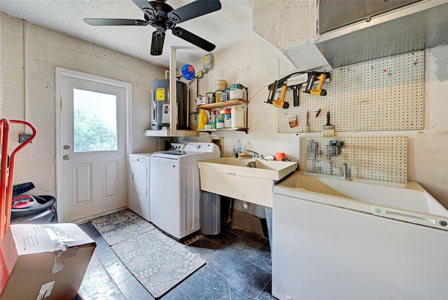 clothes washing area with a textured ceiling, a workshop area, ceiling fan, water heater, and separate washer and dryer