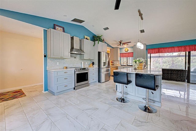 kitchen featuring ceiling fan, wall chimney exhaust hood, backsplash, vaulted ceiling, and appliances with stainless steel finishes