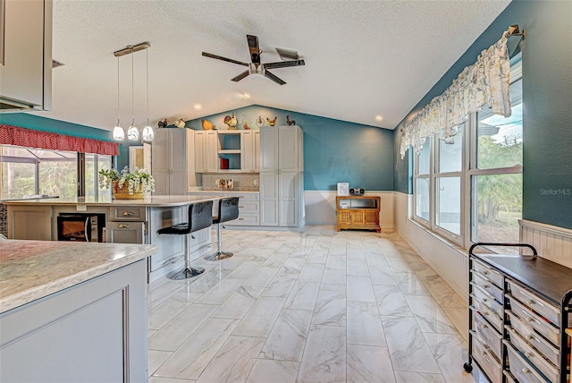 kitchen with pendant lighting, lofted ceiling, a textured ceiling, and wine cooler