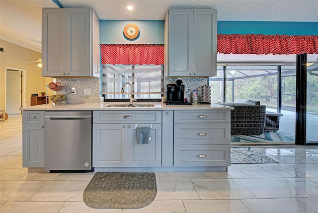 kitchen featuring sink, stainless steel dishwasher, a textured ceiling, gray cabinets, and decorative backsplash