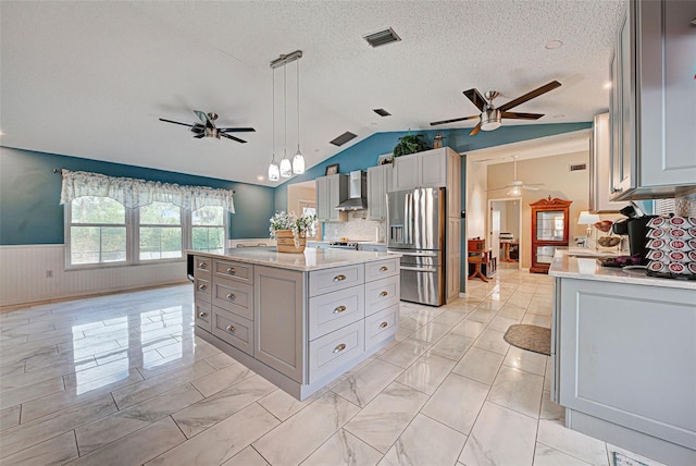 kitchen featuring wall chimney exhaust hood, pendant lighting, stainless steel fridge with ice dispenser, a kitchen island, and lofted ceiling