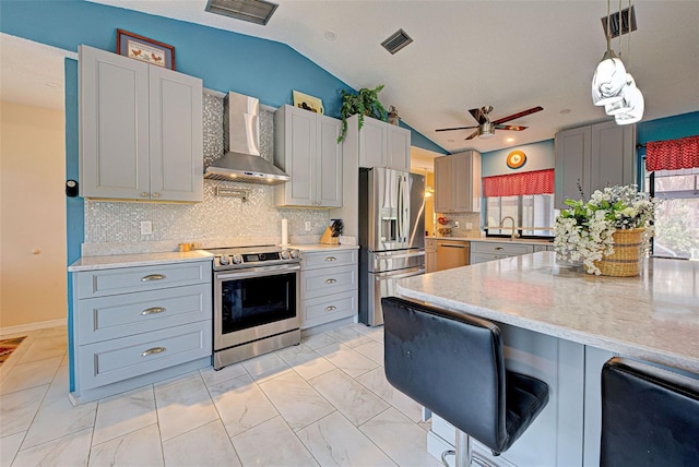 kitchen featuring lofted ceiling, sink, hanging light fixtures, wall chimney exhaust hood, and appliances with stainless steel finishes