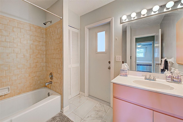 bathroom with vanity, a healthy amount of sunlight, a textured ceiling, and tiled shower / bath combo