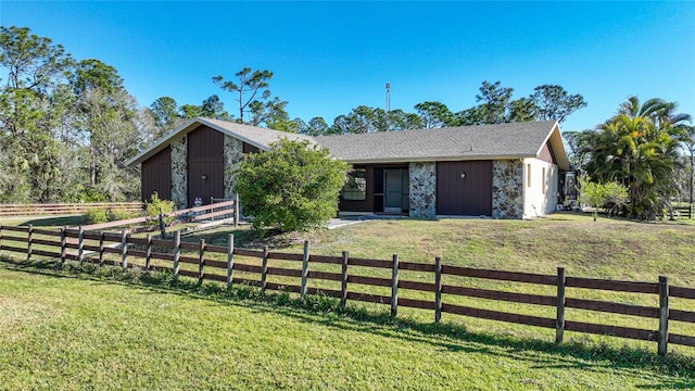 view of front of home featuring stone siding, a front yard, and fence