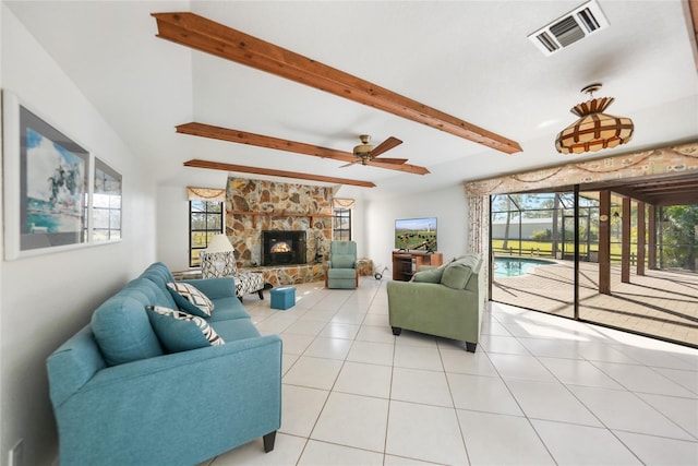 tiled living room featuring a stone fireplace, ceiling fan, and beamed ceiling