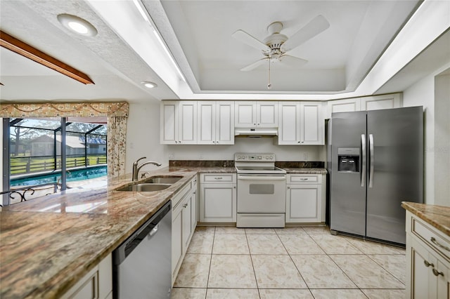 kitchen with light tile patterned floors, stainless steel appliances, a raised ceiling, a sink, and under cabinet range hood