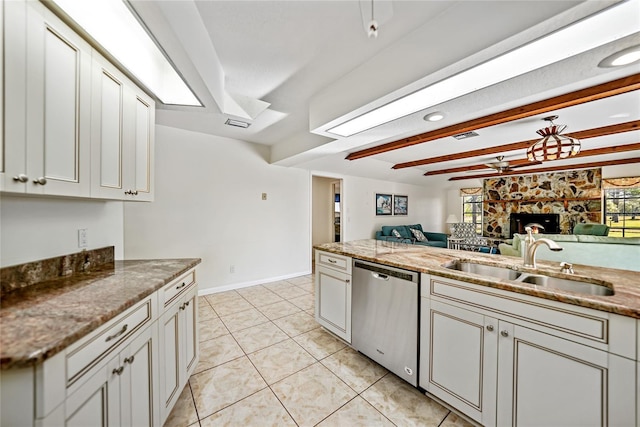 kitchen with sink, a stone fireplace, stainless steel dishwasher, stone countertops, and light tile patterned floors