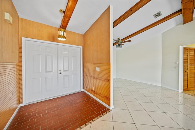 foyer featuring visible vents, a ceiling fan, lofted ceiling with beams, brick floor, and wood walls