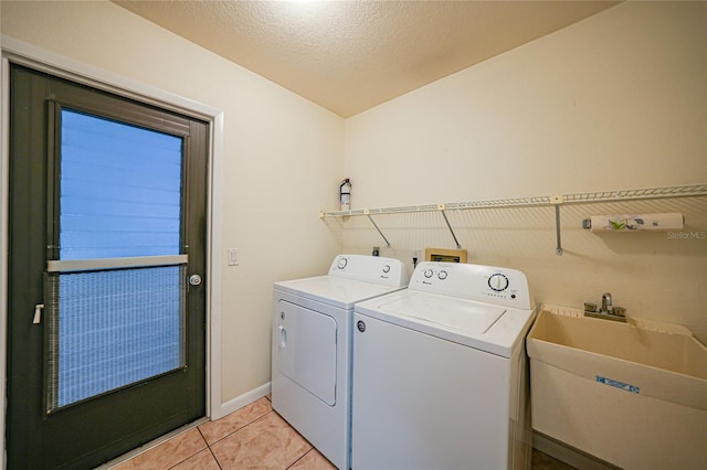 laundry area featuring a textured ceiling, washer and dryer, light tile patterned floors, and sink