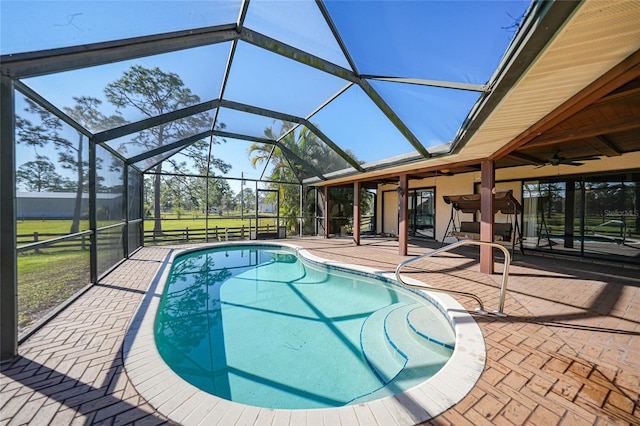 view of pool with glass enclosure, ceiling fan, and a patio area