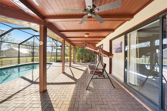 exterior space featuring glass enclosure, a ceiling fan, and an outdoor pool