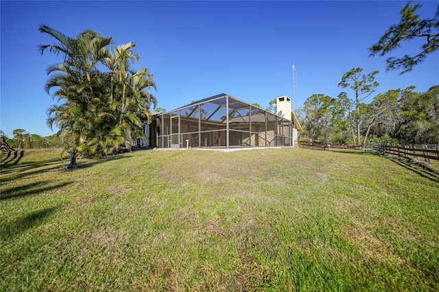 view of yard with glass enclosure and fence