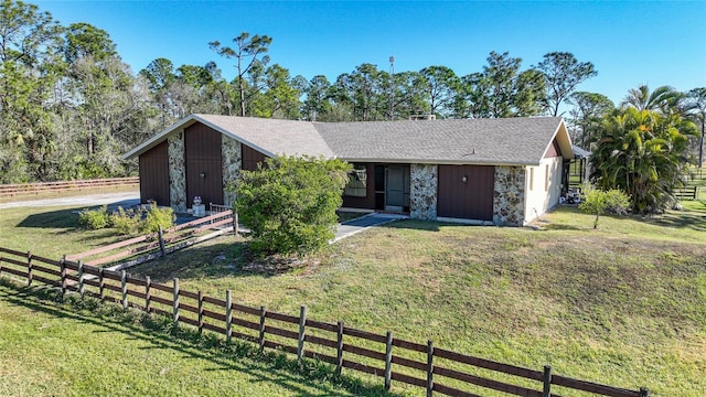 view of front facade with stone siding, fence, and a front yard