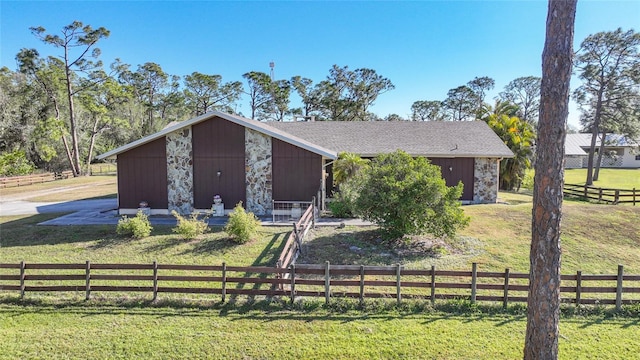 view of front facade with a front yard, stone siding, and fence