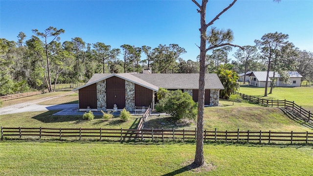 view of front facade with a rural view, an outbuilding, and a front yard